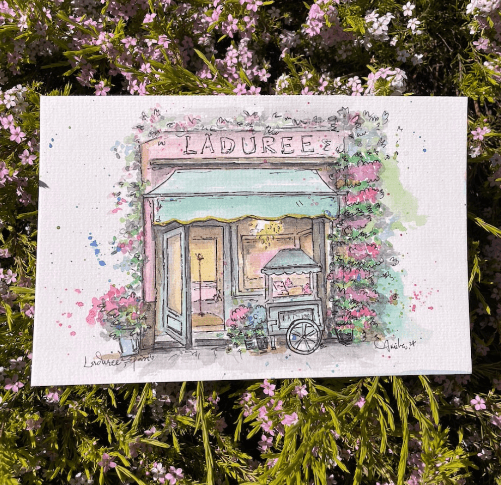 Watercolor painting of Laduree bakery storefront with floral decorations, surrounded by pink flowers.