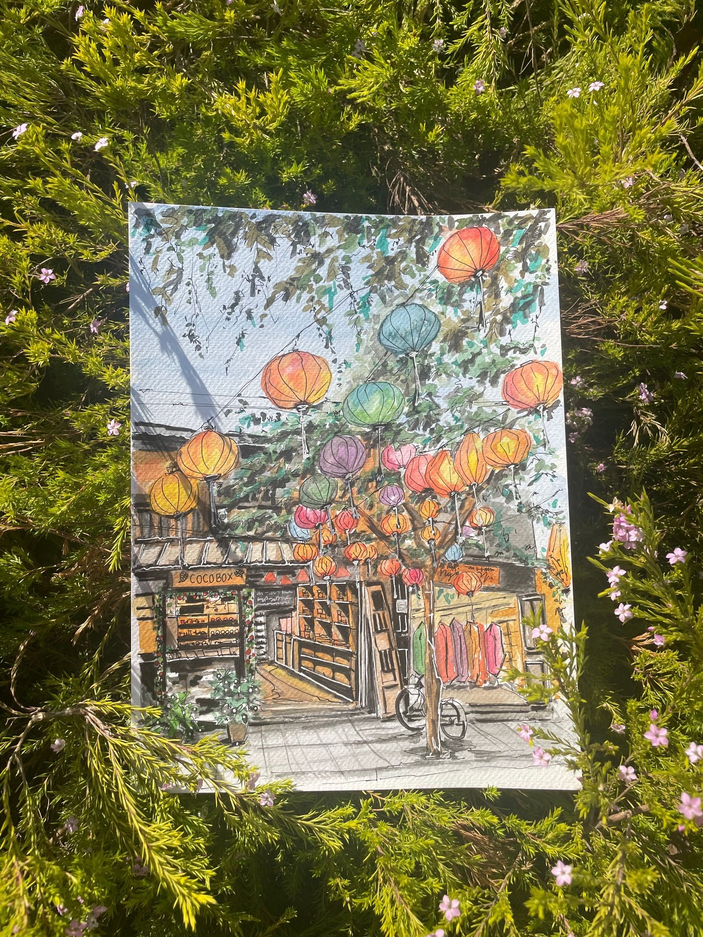 Colorful lanterns sketch on canvas, placed on green foliage.